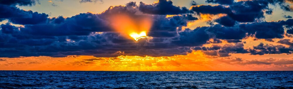 Picture of sunrise, with heart-shaped sunbeam between the clouds.